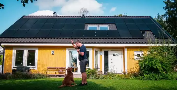 homme et chien devant panneaux solaires maison